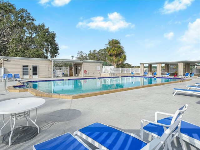 community pool with a patio area and fence