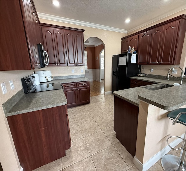 kitchen with arched walkways, a textured ceiling, a sink, black appliances, and crown molding