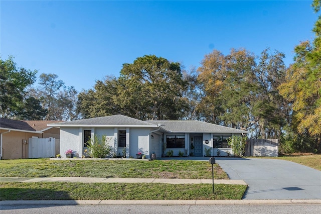 view of front of home featuring stucco siding, a front yard, driveway, and fence