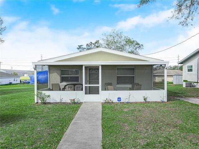 view of front of property with a front yard, a sunroom, central air condition unit, and stucco siding