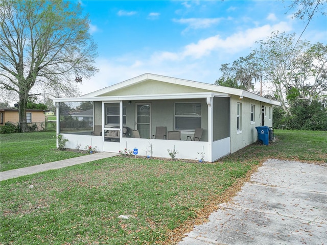 view of front of home with a front yard and a sunroom