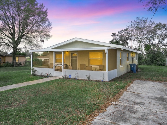 view of front facade featuring a sunroom, a front lawn, and stucco siding