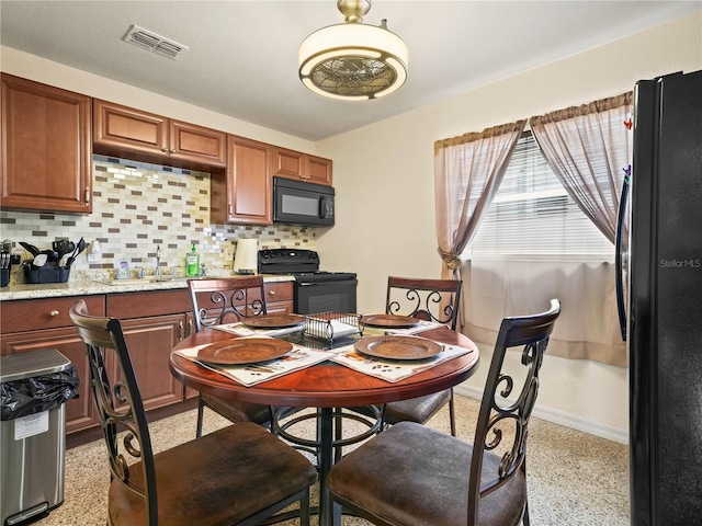 kitchen featuring light speckled floor, visible vents, baseboards, decorative backsplash, and black appliances