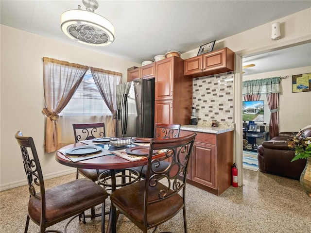 dining room featuring light speckled floor and baseboards