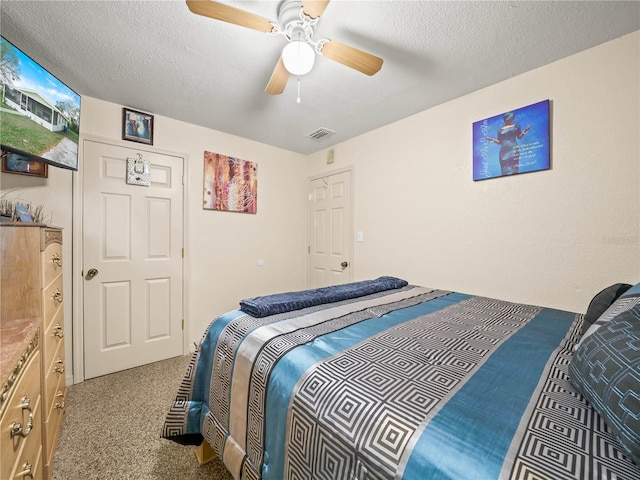 bedroom with carpet, visible vents, ceiling fan, and a textured ceiling