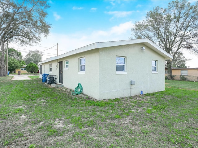 view of property exterior with central AC, a lawn, and stucco siding