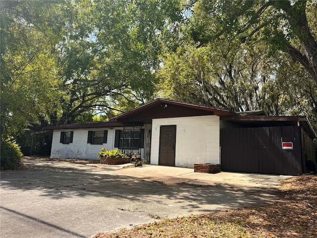 view of front of house featuring a carport, concrete block siding, and driveway