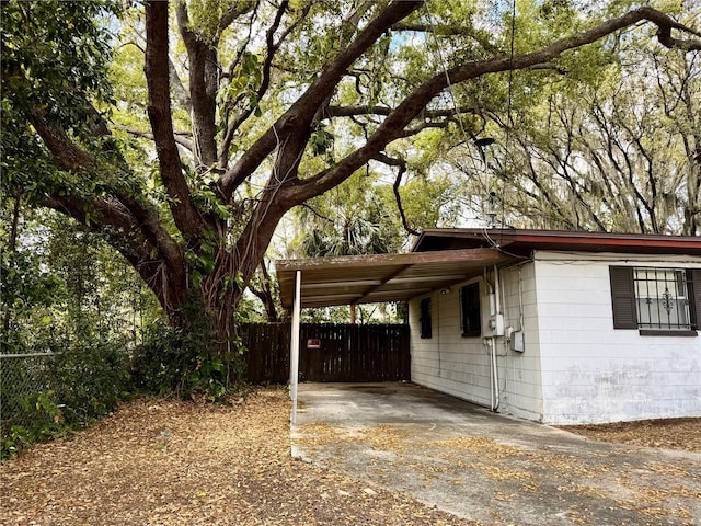 view of side of home with driveway, an attached carport, and fence