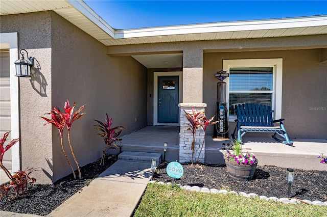 property entrance with covered porch and stucco siding