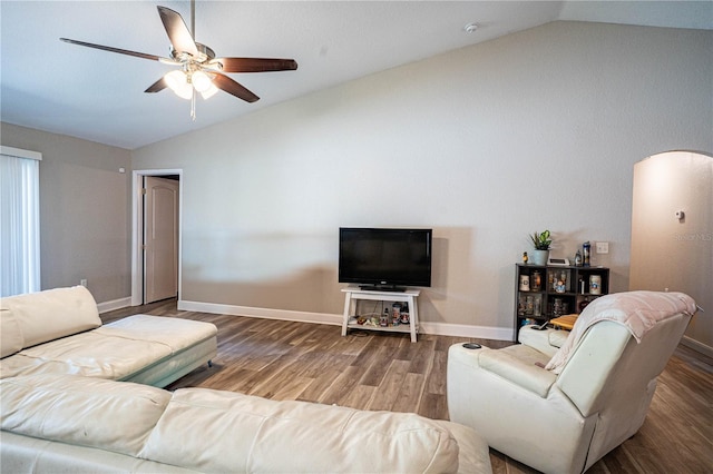 living room featuring vaulted ceiling, arched walkways, wood finished floors, and baseboards