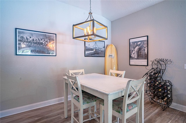 dining room with a notable chandelier, a textured ceiling, wood finished floors, and baseboards