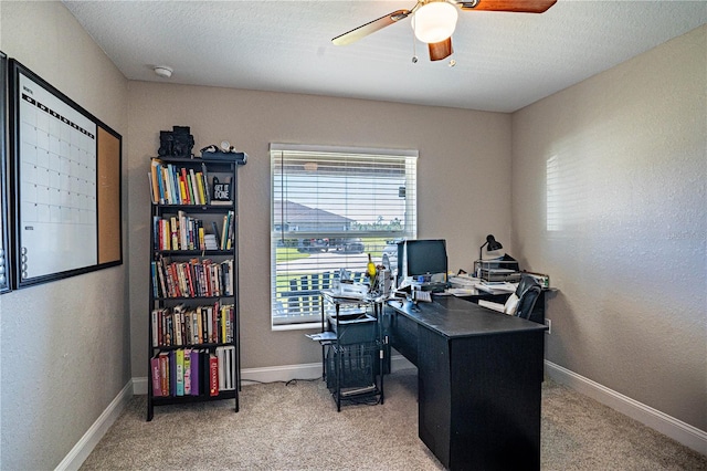 carpeted home office featuring ceiling fan, a textured wall, a textured ceiling, and baseboards