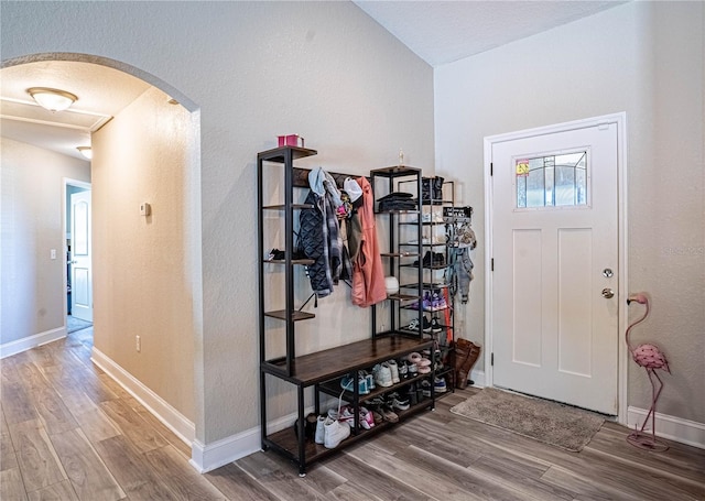 mudroom featuring baseboards, arched walkways, and wood finished floors