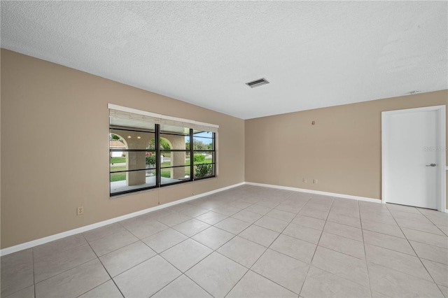 unfurnished room with light tile patterned floors, baseboards, visible vents, and a textured ceiling