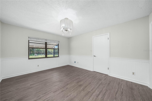 spare room with a wainscoted wall, a textured ceiling, and wood finished floors