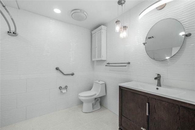 bathroom featuring toilet, visible vents, vanity, tile walls, and tile patterned floors