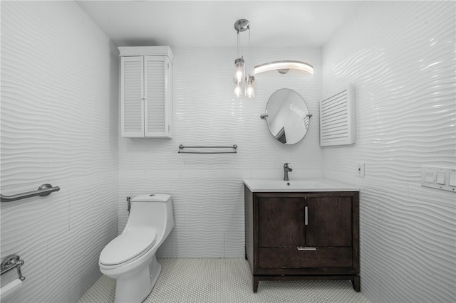 bathroom featuring toilet, tile patterned floors, tile walls, and vanity