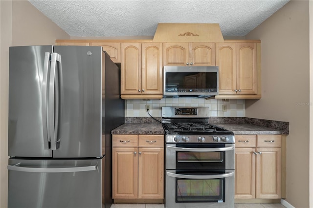 kitchen featuring appliances with stainless steel finishes, dark countertops, light brown cabinets, and tasteful backsplash