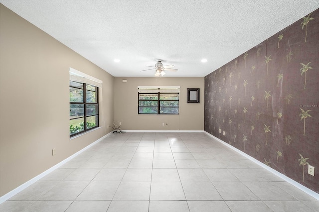 unfurnished room with an accent wall, ceiling fan, a textured ceiling, and baseboards