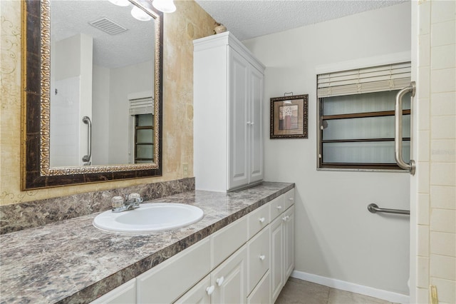 bathroom with visible vents, a textured ceiling, vanity, tile patterned flooring, and baseboards