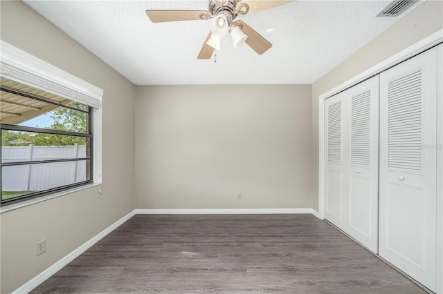 unfurnished bedroom featuring a closet, visible vents, a textured ceiling, and wood finished floors