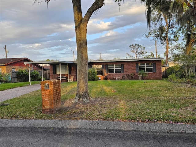 single story home featuring brick siding, fence, a front yard, decorative driveway, and a carport