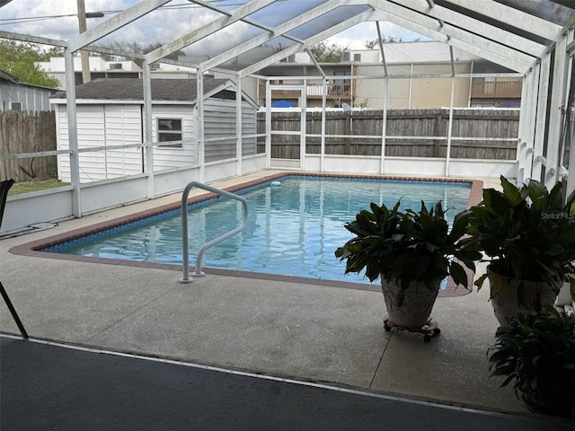 view of swimming pool with a fenced in pool, an outbuilding, glass enclosure, and a fenced backyard