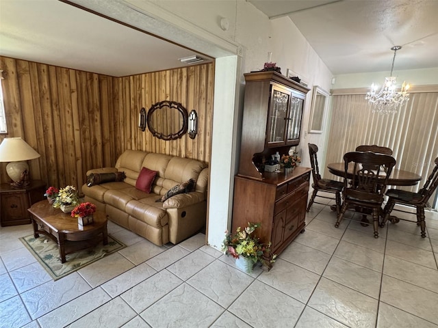 living room featuring light tile patterned floors, visible vents, wooden walls, and a chandelier