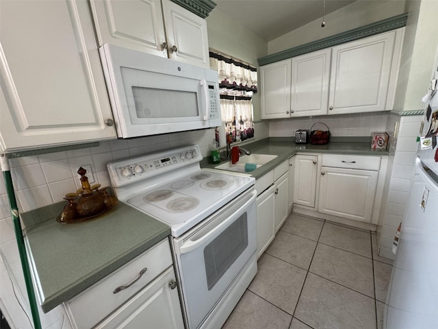 kitchen featuring white appliances, tasteful backsplash, white cabinets, a sink, and light tile patterned flooring