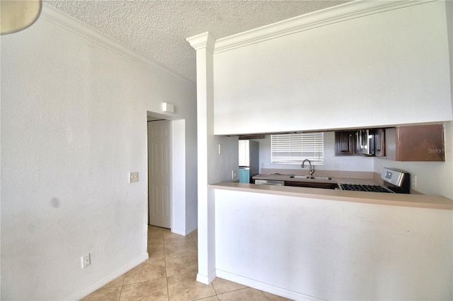 kitchen featuring a textured ceiling, light tile patterned flooring, stainless steel appliances, a sink, and crown molding