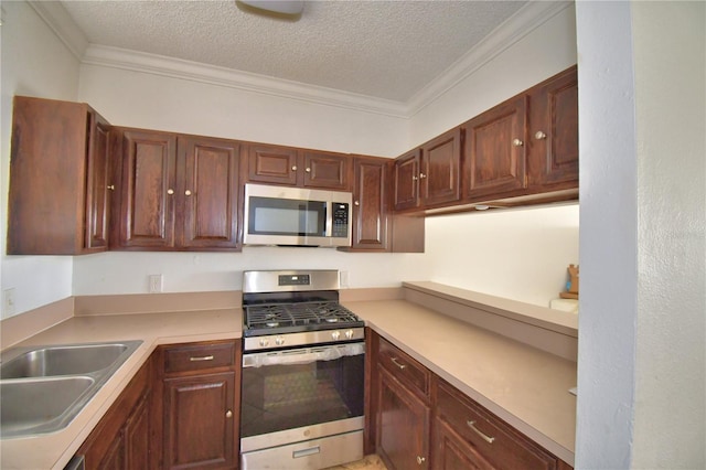 kitchen featuring ornamental molding, stainless steel appliances, a textured ceiling, light countertops, and a sink