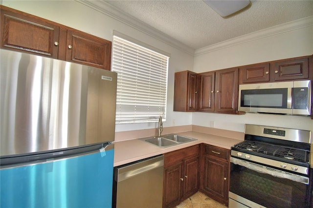 kitchen with appliances with stainless steel finishes, ornamental molding, light countertops, a textured ceiling, and a sink