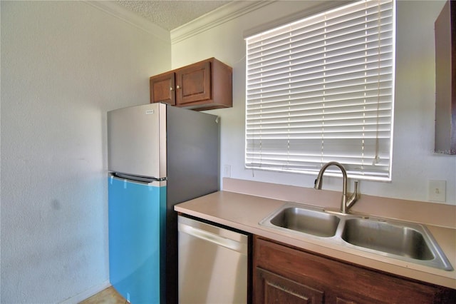 kitchen featuring brown cabinets, stainless steel appliances, crown molding, light countertops, and a sink