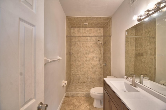 bathroom featuring a tile shower, vanity, toilet, and tile patterned floors