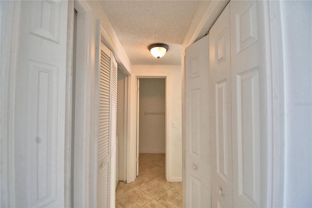 corridor with light tile patterned floors and a textured ceiling