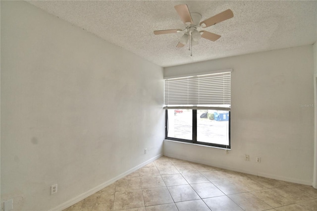 spare room featuring ceiling fan, a textured ceiling, baseboards, and light tile patterned floors