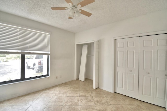 unfurnished bedroom with light tile patterned floors, ceiling fan, and a textured ceiling