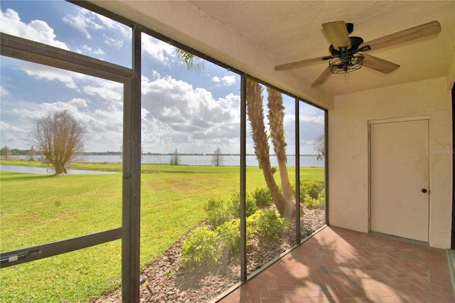 unfurnished sunroom with plenty of natural light, a water view, and a ceiling fan