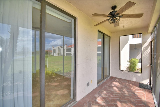 unfurnished sunroom with ceiling fan