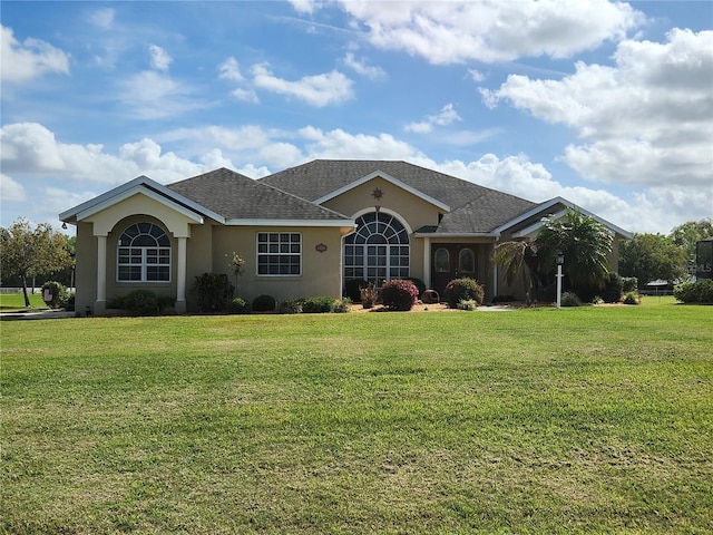 ranch-style house with stucco siding, a front lawn, and roof with shingles