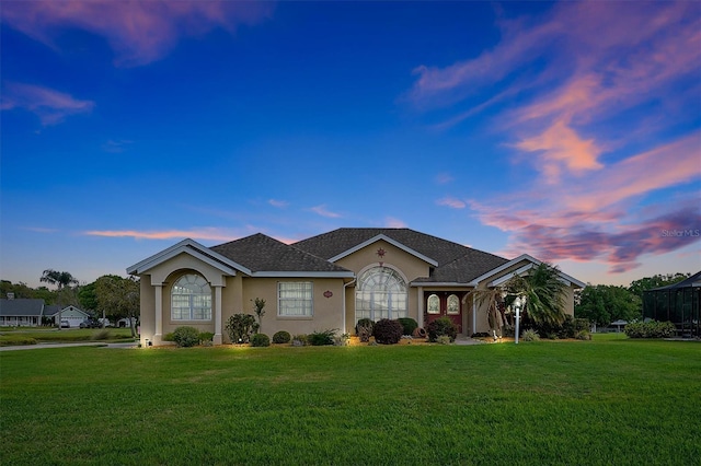 ranch-style house featuring stucco siding, roof with shingles, and a front yard