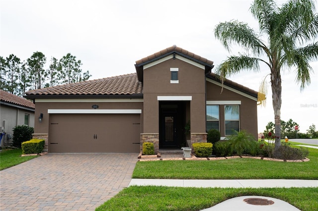 mediterranean / spanish house with decorative driveway, stone siding, stucco siding, and a tiled roof