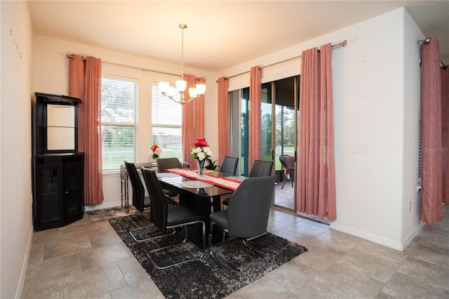 dining space with baseboards, a notable chandelier, and stone finish floor