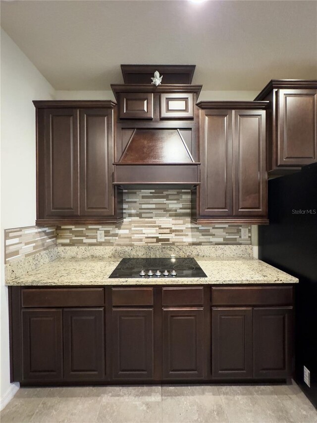 kitchen featuring decorative backsplash, custom exhaust hood, black appliances, and dark brown cabinetry