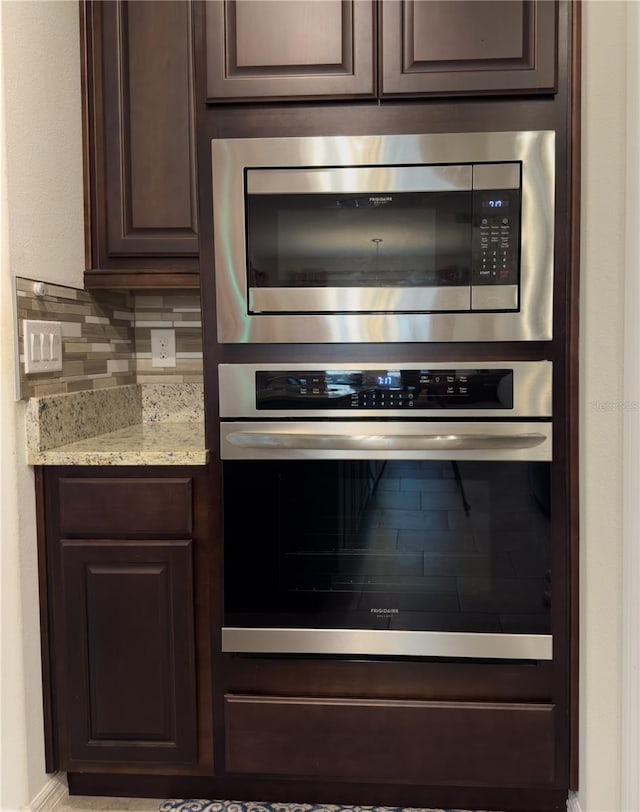 kitchen featuring dark brown cabinetry, appliances with stainless steel finishes, tasteful backsplash, and light stone counters