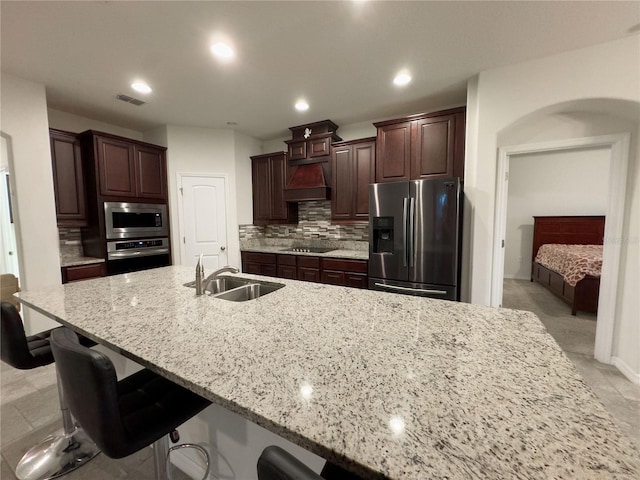 kitchen with visible vents, custom exhaust hood, a sink, decorative backsplash, and stainless steel appliances