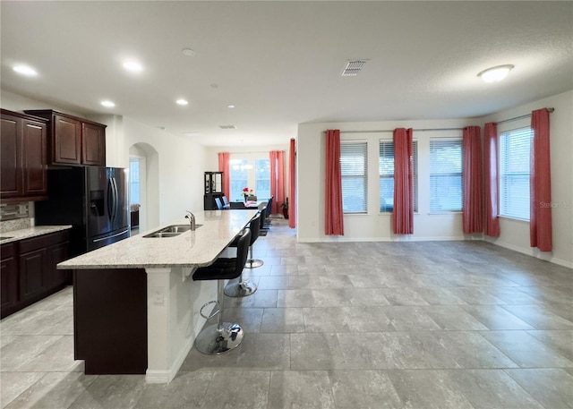 kitchen with visible vents, a breakfast bar area, refrigerator with ice dispenser, arched walkways, and a sink