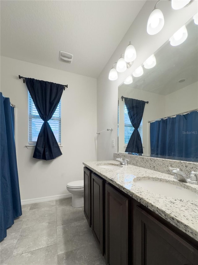 full bathroom featuring a sink, visible vents, toilet, and double vanity