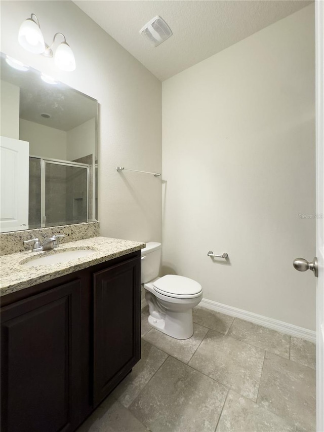 bathroom featuring visible vents, toilet, a shower stall, baseboards, and vanity