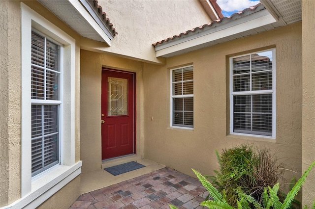 property entrance with a tiled roof and stucco siding